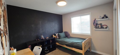 Room featuring a prominent accent wall, a flush-mount ceiling light fixture, and a window with blinds - 4234 46 Street, Vegreville, AB - Indoor Photo Showing Bedroom