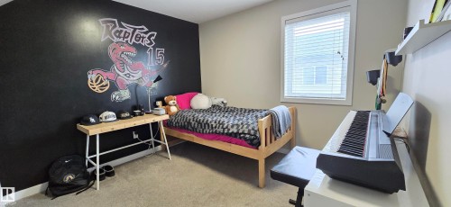 Spacious bedroom featuring light-colored carpet flooring, a single window with blinds, and a bold accent wall - 4234 46 Street, Vegreville, AB - Indoor Photo Showing Bedroom