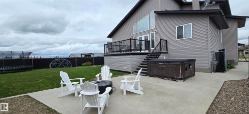 Expansive concrete patio with a built-in fire pit, offering direct access to the lower-level spa - 4234 46 Street, Vegreville, AB - Outdoor With Deck Patio Veranda With Exterior