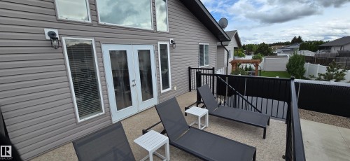 Upper-level outdoor patio with gray siding exterior, white-framed French doors, and black metal railings - 4234 46 Street, Vegreville, AB - Outdoor With Exterior
