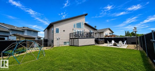 Expansive green lawn with a modern two-story residence featuring a private upper deck with dark railings - 4234 46 Street, Vegreville, AB - Outdoor With Deck Patio Veranda With Exterior