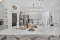 Kitchen featuring a quartz-finish island with seating, pendant lighting, white shaker-style cabinetry, subway tile backsplash, and a stainless steel refrigerator - 