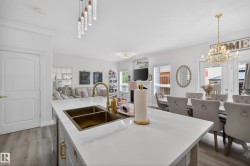 Kitchen island featuring a white countertop with a gold-tone double basin sink and a matching gold-tone faucet - 