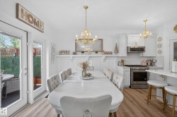 Open-concept living space featuring wood-finish flooring, white paneled wainscoting, and French doors leading to an outdoor area - 
