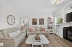 Living area featuring wood-finish flooring, white crown molding, and a built-in fireplace with a dark stone surround and white mantel - 