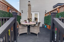 Expansive dark-stained wood deck featuring decorative lattice fencing, integrated artificial greenery, and exterior wall sconces - 