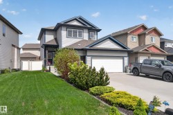 Two-story residence featuring light gray siding with dark trim accents and a two-car garage - 