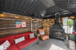 Covered outdoor living space featuring plank wood walls, a black metal roof, and string lighting - 
