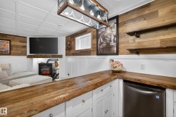 Live-edge wood countertops with white shaker-style cabinetry, a stainless steel under-counter appliance, and a coffered ceiling - 