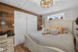 Recessed window with white trim, wood-finish flooring, white paneled closet doors, and a wood plank accent wall - 
