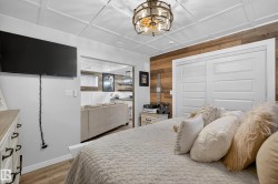 Bedroom featuring a wood-panel accent wall and white paneled sliding closet doors - 