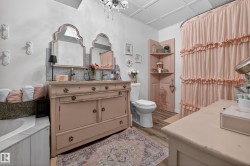 Bathroom featuring a dual vanity with ornate mirrors, a patterned area rug, a built-in corner shelving unit, a white toilet, and wood-finish flooring - 
