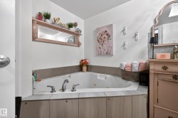 Corner soaking tub with polished chrome fixtures, surrounded by neutral-toned tile and wood-finish paneling - 