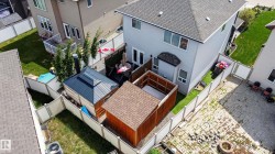 Fenced backyard featuring a large paved patio, a wood-sided shed with a shingled roof, a grey-sided structure with a dark metal roof, and a privacy-fenced area - 