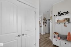 Entryway featuring wood-finish flooring, white paneled doors with brushed nickel hardware, and white baseboards - 