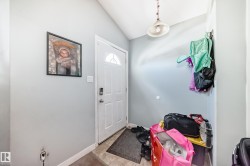 Entryway featuring a white paneled door with an arched glass insert, light gray walls, and a ceiling-mounted pendant light fixture - 