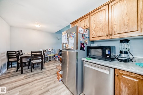 Open-concept kitchen and dining area featuring wood-finish flooring, light wood cabinetry, and a stainless steel dishwasher - 10017 153 Street, Edmonton, AB - Indoor