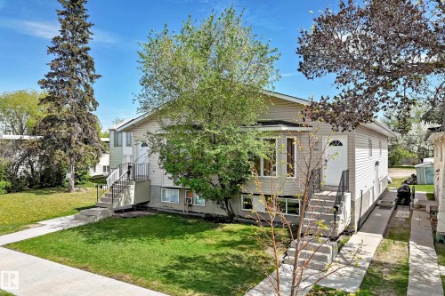 Duplex exterior featuring light-toned siding, concrete walkways, and separate entrances - 10017 153 Street, Edmonton, AB - Outdoor