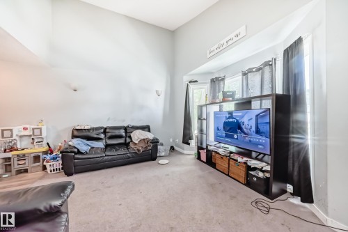 Spacious living area featuring vaulted ceilings, bay windows, light gray walls, and wall-mounted sconces - 10017 153 Street, Edmonton, AB - Indoor