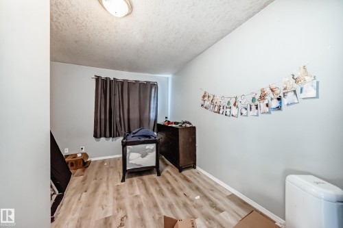 Room featuring light wood-finish flooring, light gray walls, and a window with dark curtains - 10017 153 Street, Edmonton, AB - Indoor