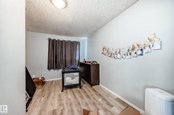 Room featuring light wood-finish flooring, light gray walls, and a window with dark curtains - 