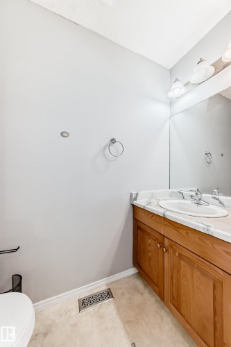 Light-toned vanity with an integrated sink, a white countertop with gray veining, and a large wall-mounted mirror with overhead lighting - 10017 153 Street, Edmonton, AB - Indoor Photo Showing Bathroom