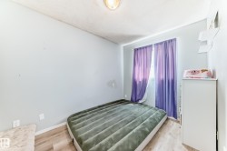 Bright interior room featuring wood-finish flooring, light blue walls, and a window with purple drapes - 