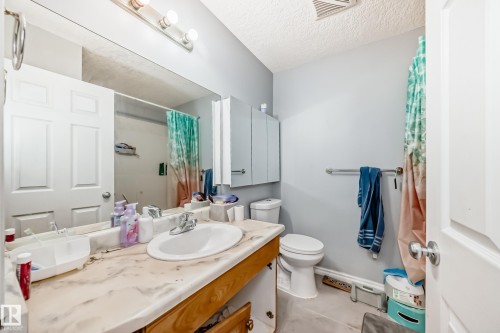 Bathroom featuring a large vanity mirror, a single basin sink, and a wood-finish vanity cabinet - 10017 153 Street, Edmonton, AB - Indoor Photo Showing Bathroom