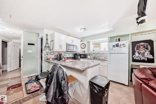 Kitchen featuring white cabinetry with brushed nickel hardware, laminate countertops, a tile backsplash, and ceramic tile flooring - 10017 153 Street, Edmonton, AB - Indoor Photo Showing Kitchen