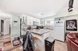 Kitchen featuring white cabinetry with brushed nickel hardware, laminate countertops, a tile backsplash, and ceramic tile flooring - 