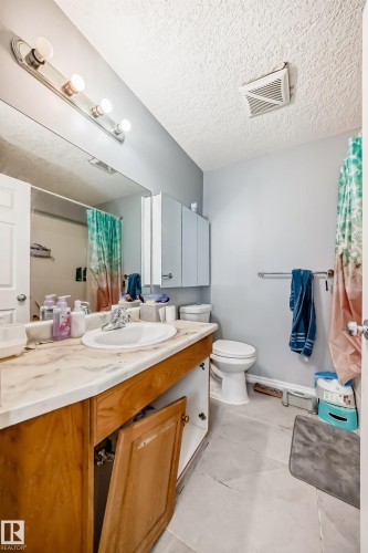 Bathroom featuring a single vanity with a laminate countertop, an integrated sink, and wood-finish cabinetry - 10017 153 Street, Edmonton, AB - Indoor Photo Showing Bathroom