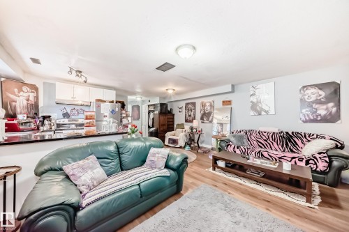 Open-concept living area featuring wood-finish flooring, recessed lighting, and a built-in breakfast bar with a black countertop - 10017 153 Street, Edmonton, AB - Indoor Photo Showing Living Room