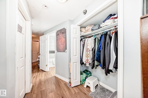 Hallway featuring wood-finish flooring, light grey painted walls, and white trim - 10017 153 Street, Edmonton, AB - Indoor With Storage