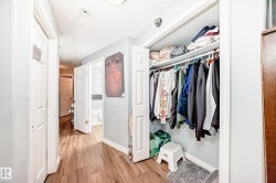 Hallway featuring wood-finish flooring, light grey painted walls, and white trim - 