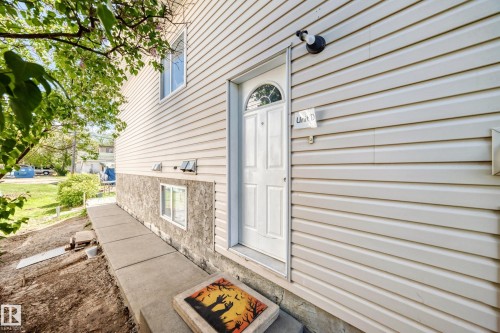 White paneled entry door with an arched glass inset, flanked by light-toned horizontal siding - 10017 153 Street, Edmonton, AB - Outdoor With Exterior
