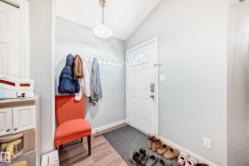 Entryway featuring a white paneled door with an arched glass insert, wood-finish flooring, light gray walls, and a recessed coat rack - 10017 153 Street, Edmonton, AB - Indoor Photo Showing Other Room