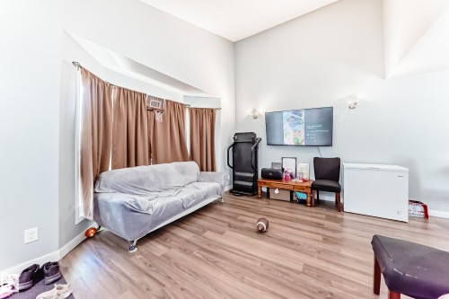 Spacious living area featuring wood-finish flooring, vaulted ceilings, and light-toned wall paint - 10017 153 Street, Edmonton, AB - Indoor
