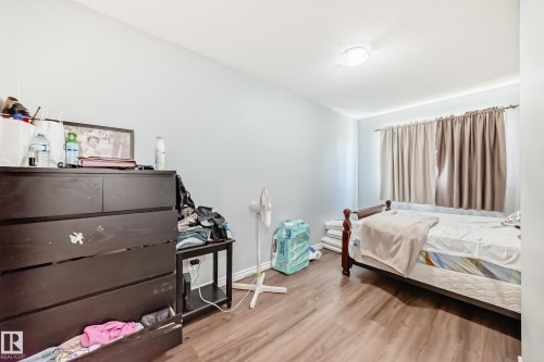 Room featuring wood-finish flooring, a neutral wall color, window with curtain rod and drapes, and an overhead flush-mount light fixture - 10017 153 Street, Edmonton, AB - Indoor Photo Showing Bedroom