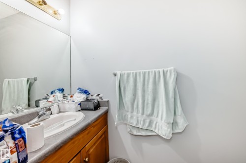 Bathroom vanity featuring a built-in sink, laminate countertop, wood-finish cabinetry, and mosaic tile backsplash - 10017 153 Street, Edmonton, AB - Indoor Photo Showing Bathroom