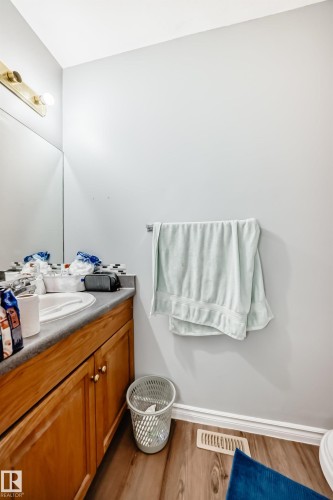 Bathroom vanity featuring wood cabinetry with brass-tone hardware, a light gray countertop, and an undermount sink - 10017 153 Street, Edmonton, AB - Indoor Photo Showing Bathroom