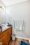 Bathroom vanity featuring wood cabinetry with brass-tone hardware, a light gray countertop, and an undermount sink - 