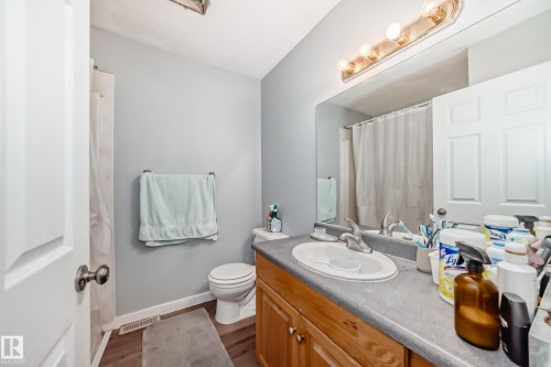 Bathroom featuring a wood-finish vanity with a built-in sink, gray countertop, and overhead vanity lighting - 10017 153 Street, Edmonton, AB - Indoor Photo Showing Bathroom