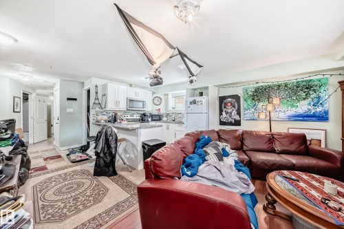 White cabinetry with stainless steel appliances and a tile backsplash in the kitchen area - 10017 153 Street, Edmonton, AB - Indoor Photo Showing Living Room