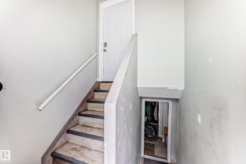 Painted interior staircase featuring a white paneled door, light-toned walls, and a white handrail - 10017 153 Street, Edmonton, AB - Indoor Photo Showing Other Room