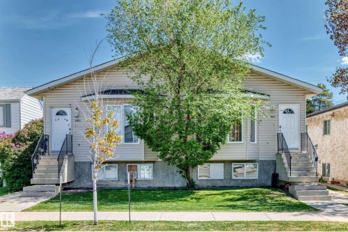 Duplex property featuring light-toned horizontal siding, a gabled roofline, and two separate entrances - 10017 153 Street, Edmonton, AB - Outdoor With Facade