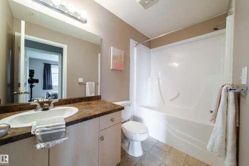 Bathroom featuring a single vanity with a laminate countertop, an undermount sink, and light wood cabinetry - 115 4309 33 Street, Stony Plain, AB 