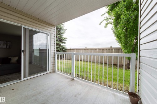 Covered concrete patio featuring white railing, direct access to the interior via a sliding glass door, and an exterior of horizontal siding - 115 4309 33 Street, Stony Plain, AB 