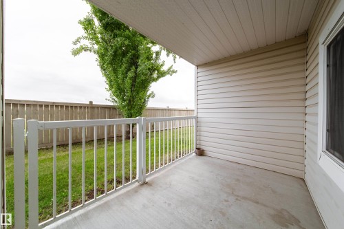 Covered concrete patio featuring white railing - 115 4309 33 Street, Stony Plain, AB 