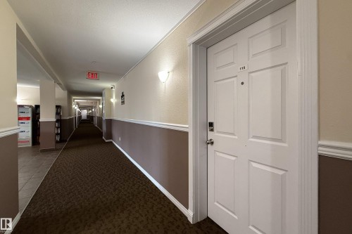 White paneled entry door with chrome hardware, featuring a digital lock and visible unit number - 115 4309 33 Street, Stony Plain, AB 