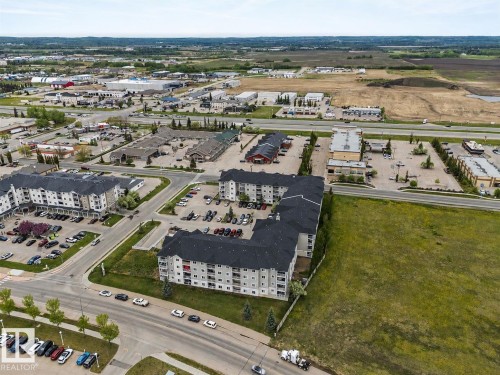 Apartment complex featuring grey and white exterior siding, a dark shingled roof, and surface parking - 115 4309 33 Street, Stony Plain, AB 
